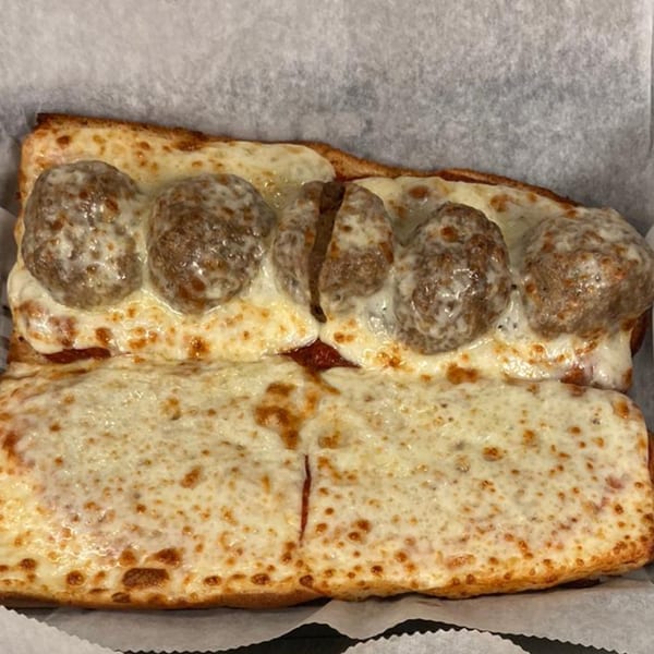 A meatball grinder from The Grinders & Spaghetti House, topped with melted cheese and sauce.