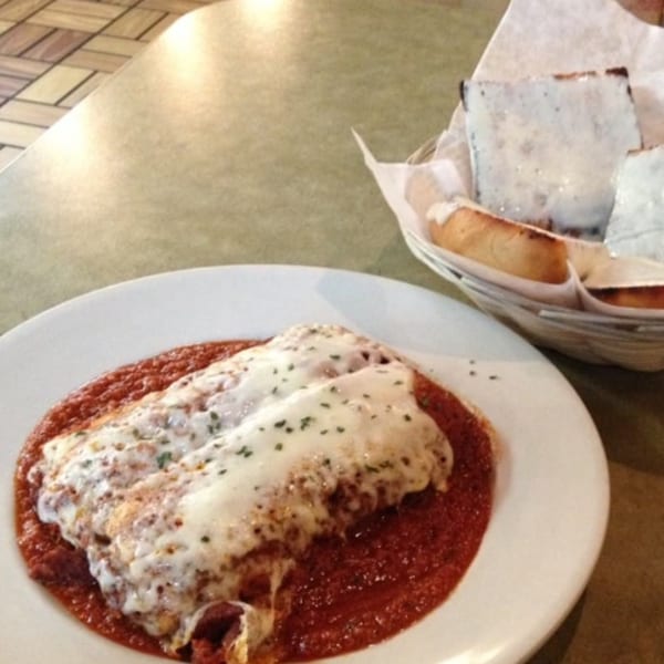 Baked lasagna with melted cheese and red sauce, with a side of cheesy garlic bread.