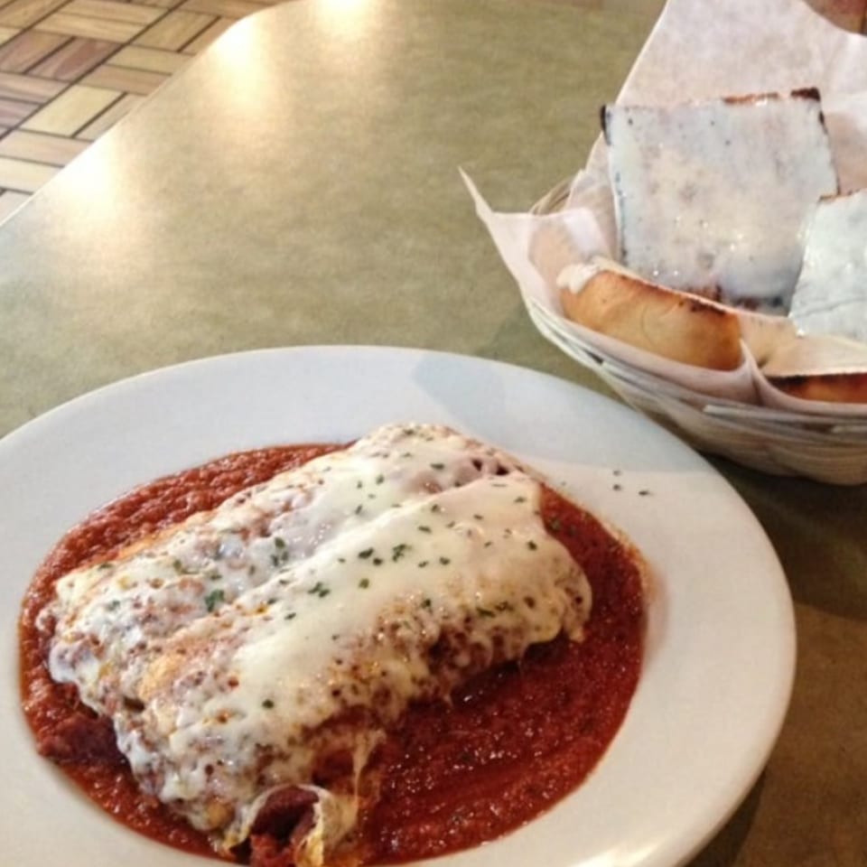 Baked lasagna with melted cheese and red sauce, with a side of cheesy garlic bread.