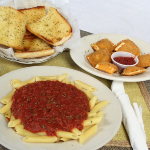 Penne pasta with red sauce, fried ravioli with marinara, and a basket of garlic bread.