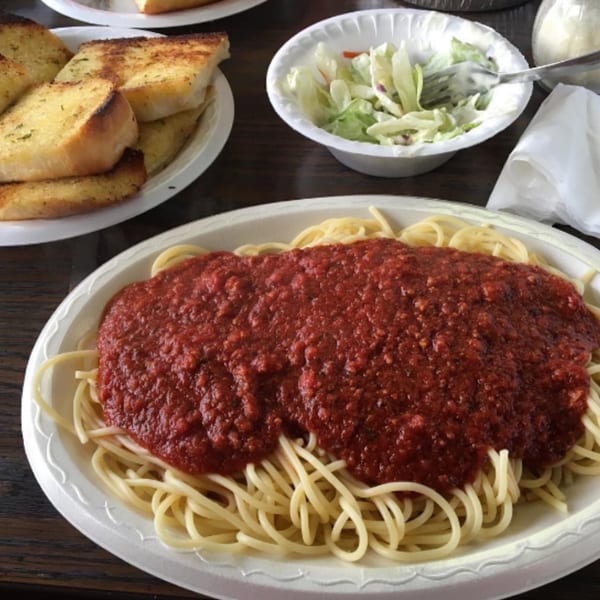 Spaghetti with red sauce, garlic bread, and a side salad in disposable containers from The Grinders & Spaghetti House.